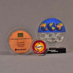 Grouping of three circular acrylic embedments awards with different items cast inside clear acrylic.