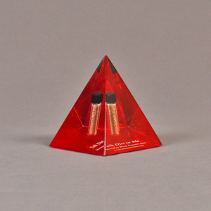 Angle view of 3 1/2" x 4 1/2" pyramid acrylic embedment award with red tint and dirt sample cast inside.