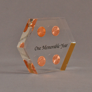 Angle view of 4" x 5" hexagon acrylic embedment award with four pennies cast in clear acrylic and black text.