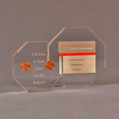 Two octagon acrylic embedment awards one with cast pennies the other with cast printed Janus Institutional Assets tagline.