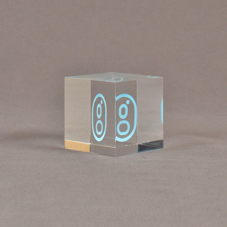 Angle view of 2" cube acrylic embedment award with G logo printed on clear acetate and cast in acrylic.