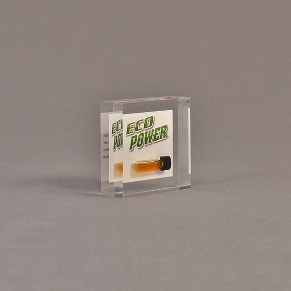Angle view of 3" square acrylic embedment award with Eco Power logo and vial of oil cast in acrylic.