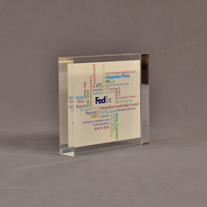 Angle view of 4 1/2" square acrylic embedment award with FedEx logo and tag lines cast in clear acrylic.