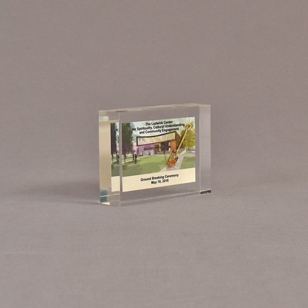 Angle view of 3" x 4" rectangle acrylic embedment award with mini ground breaking shovel and building cast in acrylic.