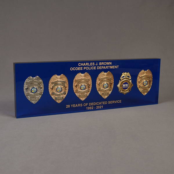 Angle view of Lucite® Badge Embedment with six career service badges cast inside clear acrylic with laser engraved text.