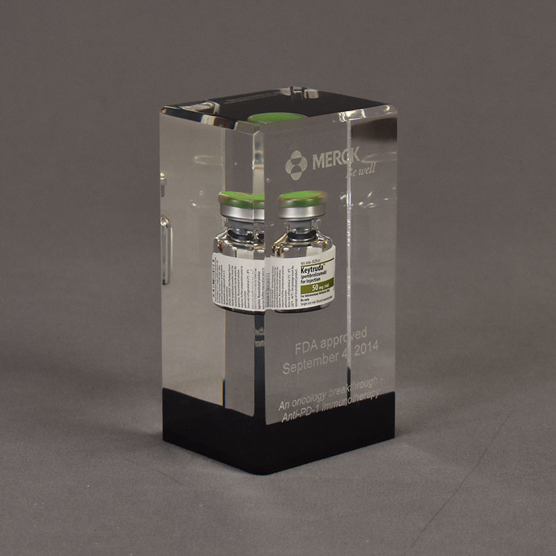 The Merck Deal Toy features and large acrylic embedded rectangular block with a high contrast black accent, cast vial and laser engraved graphics.