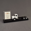 Angle view of the Best Trash Deal Toy featuring acrylic embedding, paper printing and a custom black acrylic base to house a customer supplied toy and financial tombstone.