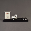Front view of the Best Trash Deal Toy featuring acrylic embedding, paper printing and a custom black acrylic base to house a customer supplied toy and financial tombstone.